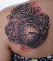 тату карманные часы с тремя розами, перо и красная лента на левой лопатке у девушки